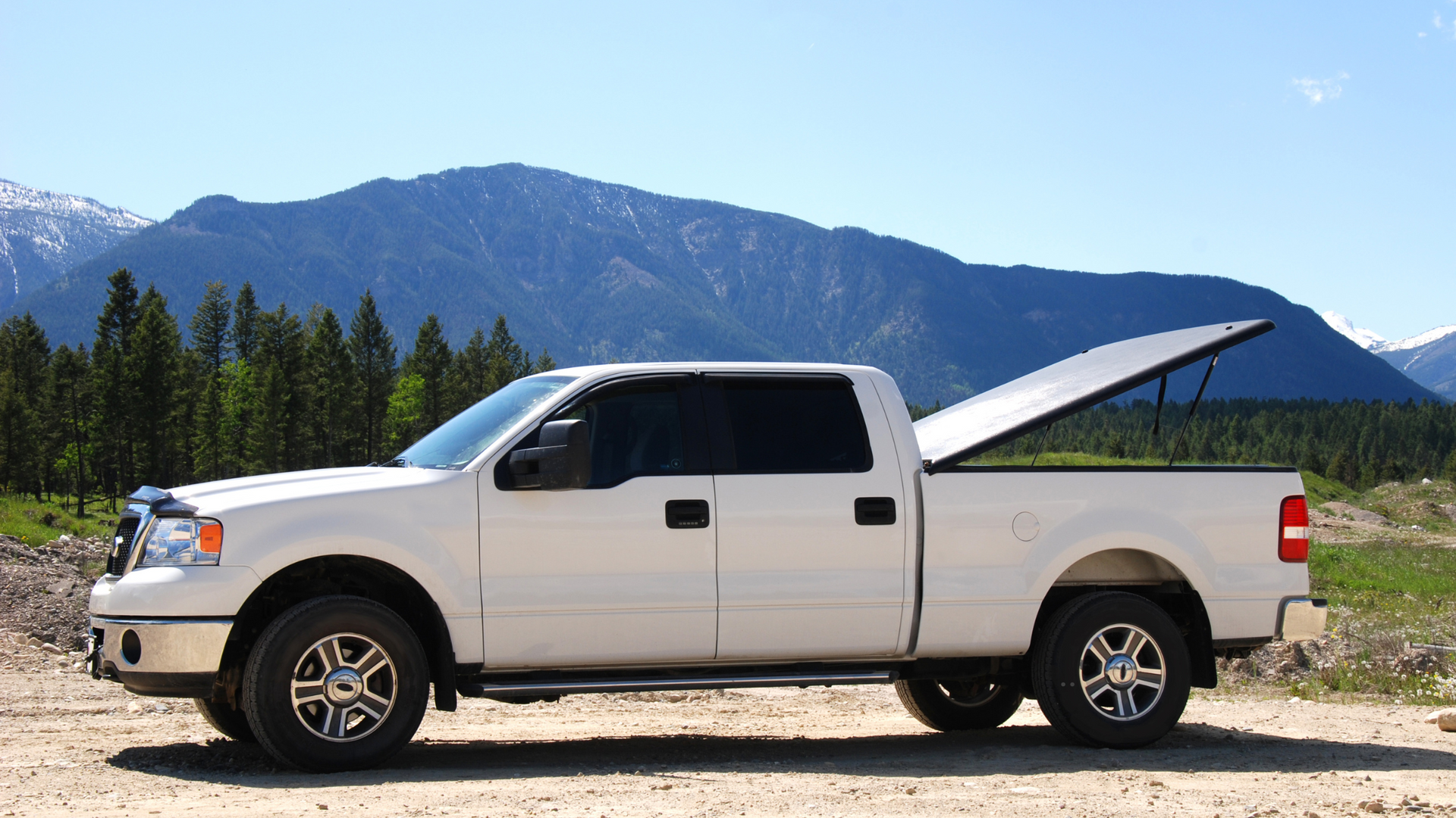 White pickup truck with the bed cover open, mountains in the background.