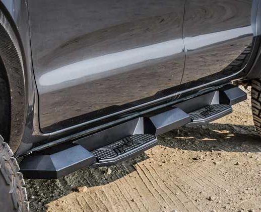 Black truck side steps installed on a vehicle, providing a stepping surface.