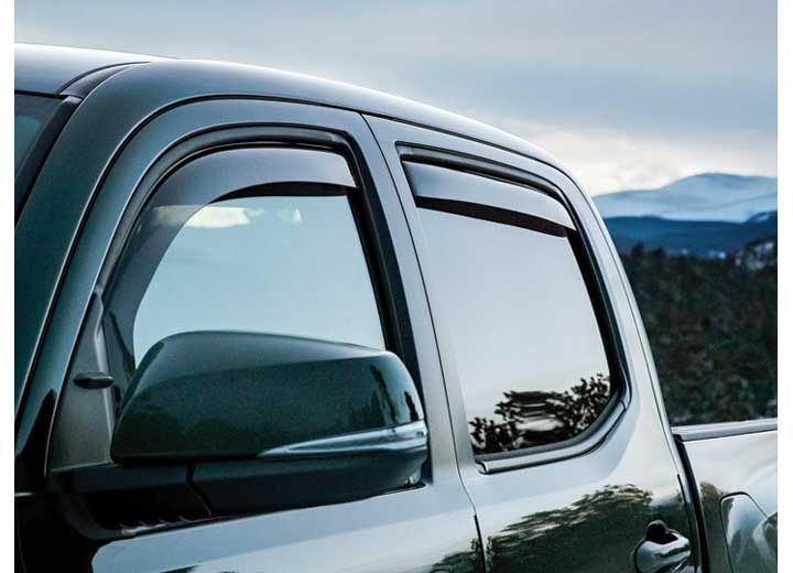 Dark green truck with window visors, side mirror visible, set against a mountain backdrop.