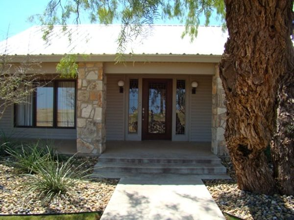 Front exterior of a home with stone accents, covered porch, and a large tree.