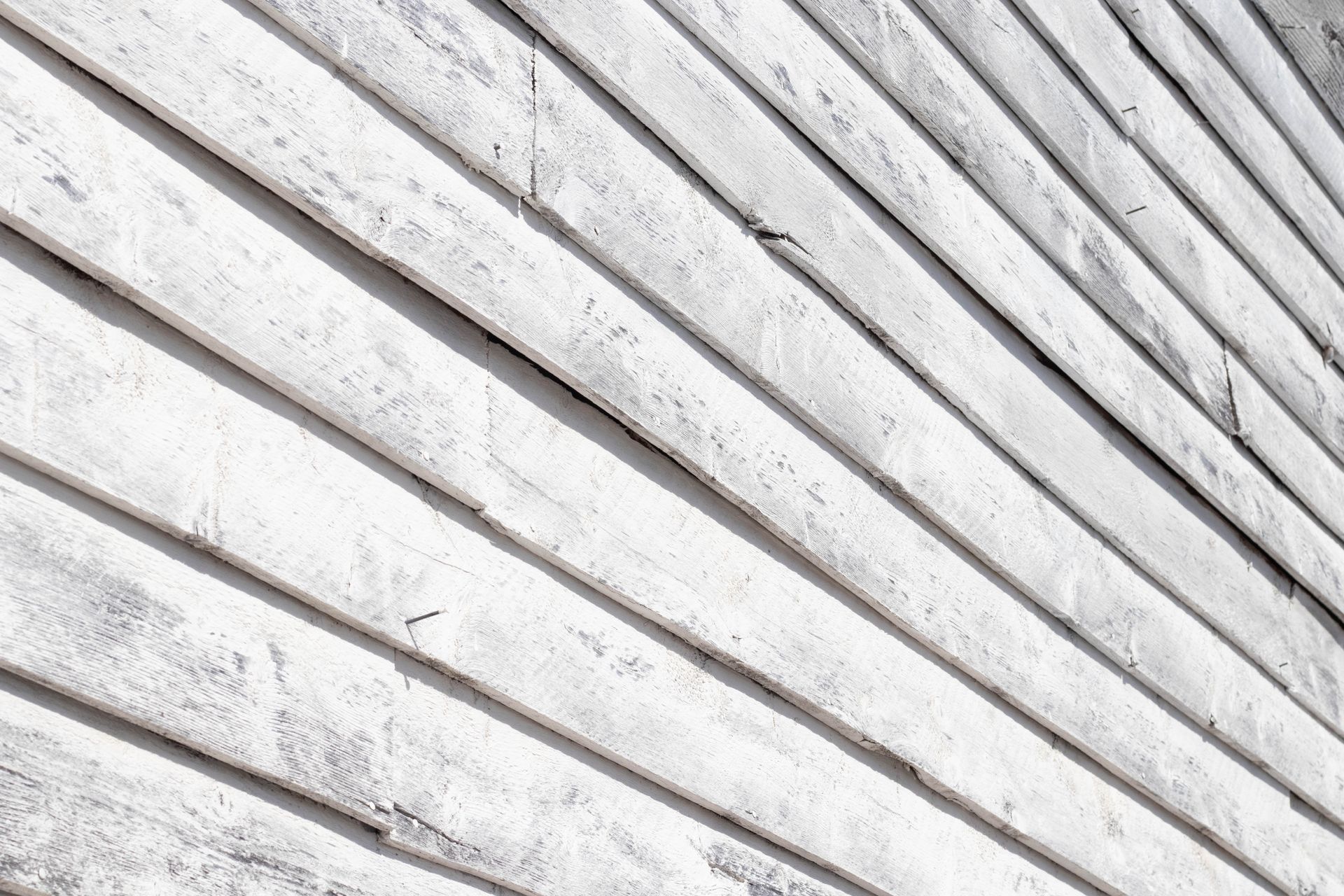 White wooden siding with diagonal boards and weathered gray streaks.