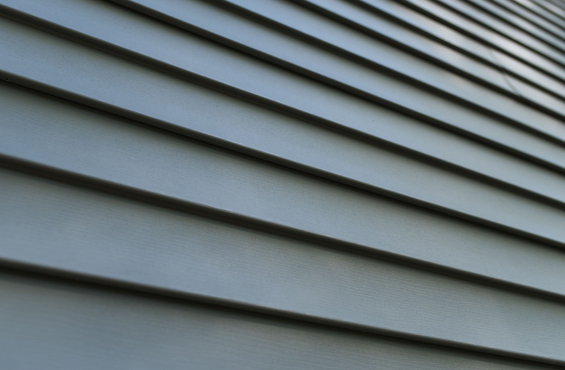 Close-up of gray house siding with horizontal overlapping panels and diagonal lines