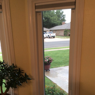 Interior view through window; white truck parked on street, green lawn and flower pot visible.