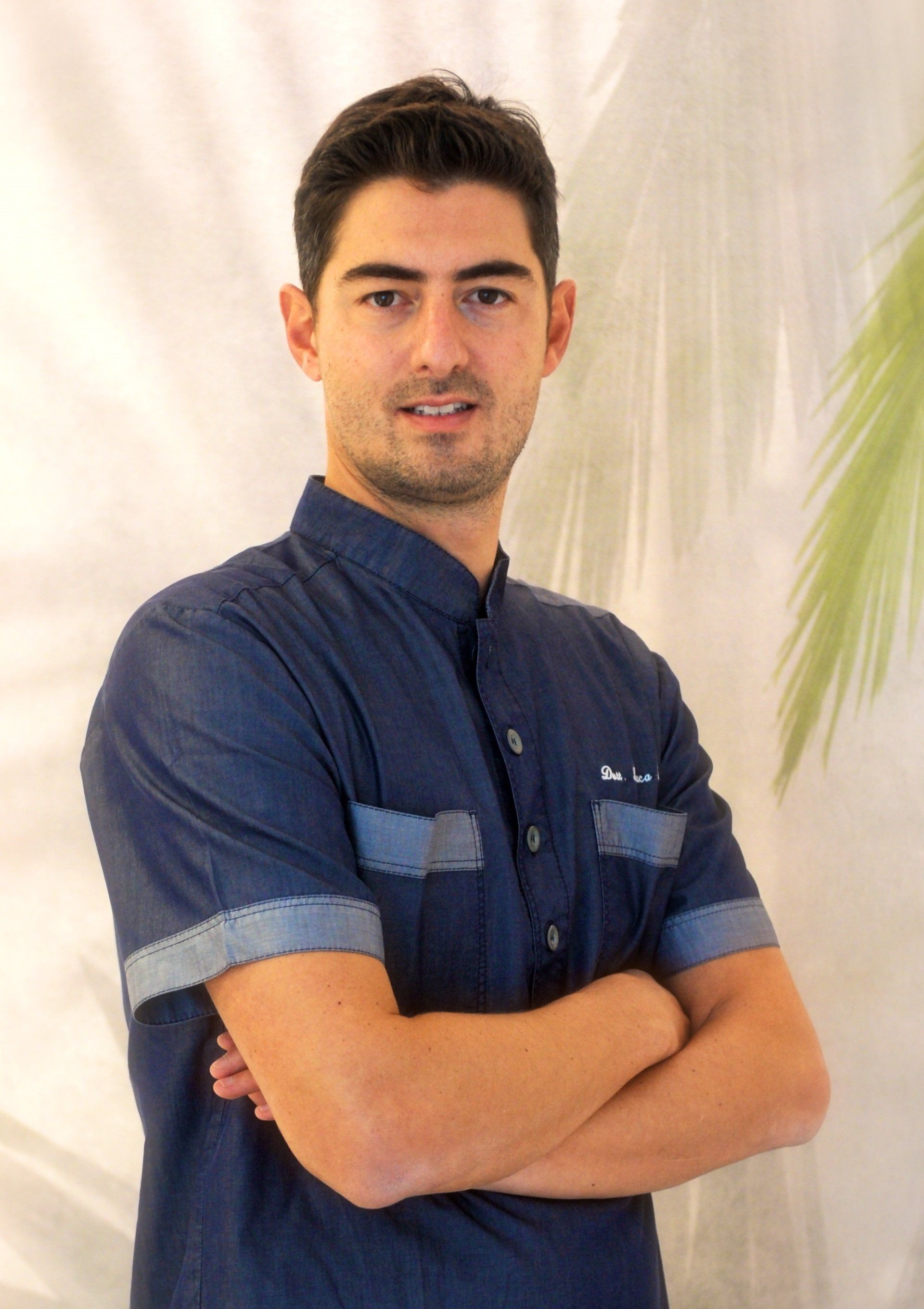 Un uomo con una camicia blu è in piedi con le braccia incrociate.