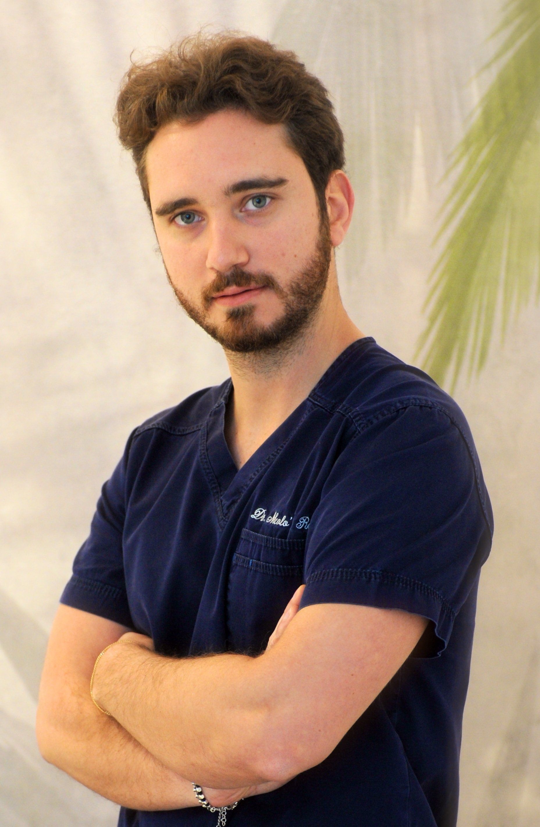 Un uomo con la barba che indossa una camicetta blu e le braccia incrociate