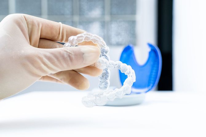 Un dentista tiene in mano un paio di apparecchi trasparenti.