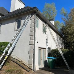 Two ladders leaning against a white two-story house under a clear blue sky.
