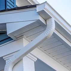 Close-up of a white house roof eave with a curved gutter and decorative trim
