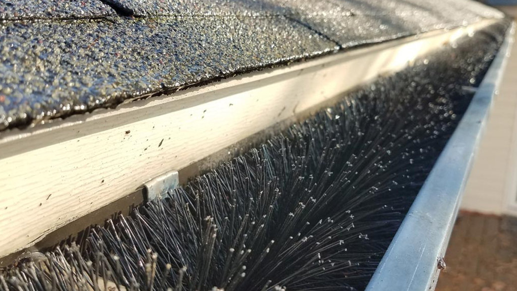 A close up of a gutter with a brush on it.