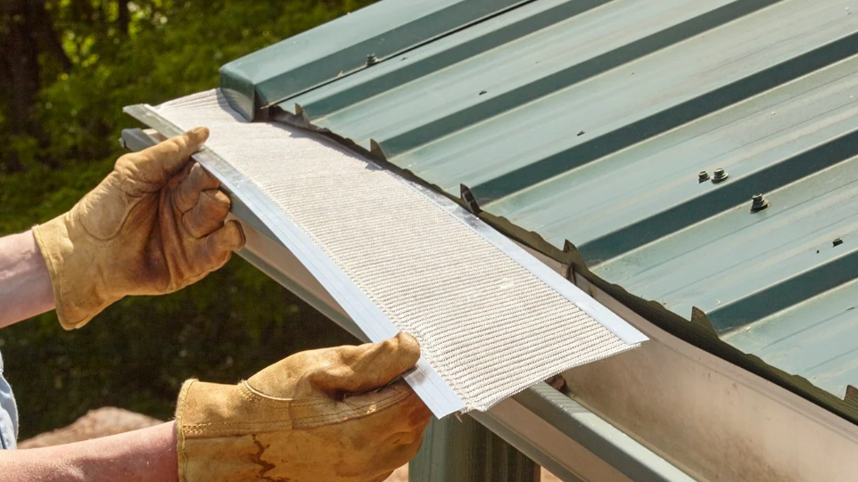 A person is installing a gutter on a metal roof.