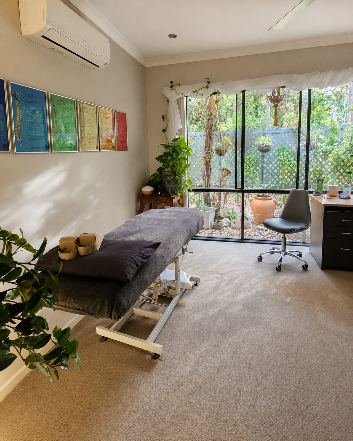 Akiki home studio with a treatment table, indoor plants and garden-facing windows