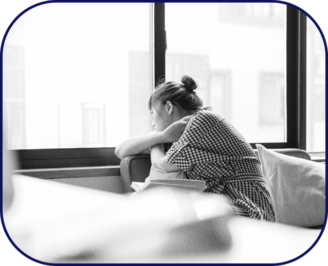 A lonely girl sitting by a window in her room