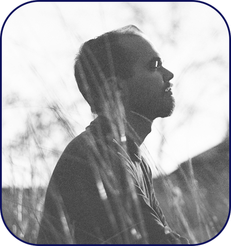 A man sitting still outdoor taking a deep breathe and reflecting