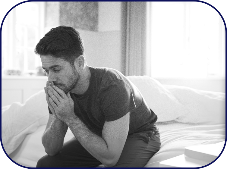 An anxious man sits on the bedside after a sleepless night.