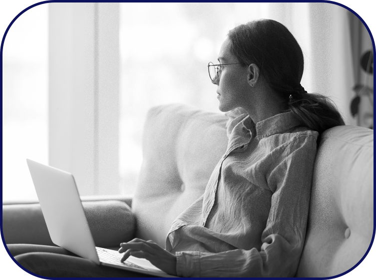 A young woman looks blankly into the distance, distracted from work because of anxiety.