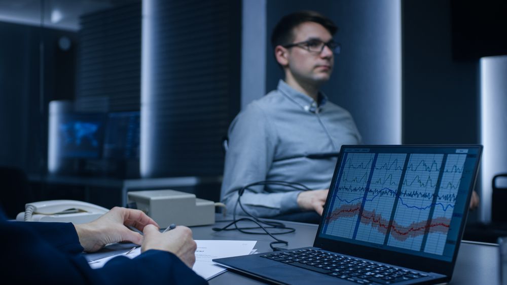 Office meeting with a man at a laptop showing charts and graphs on screen
