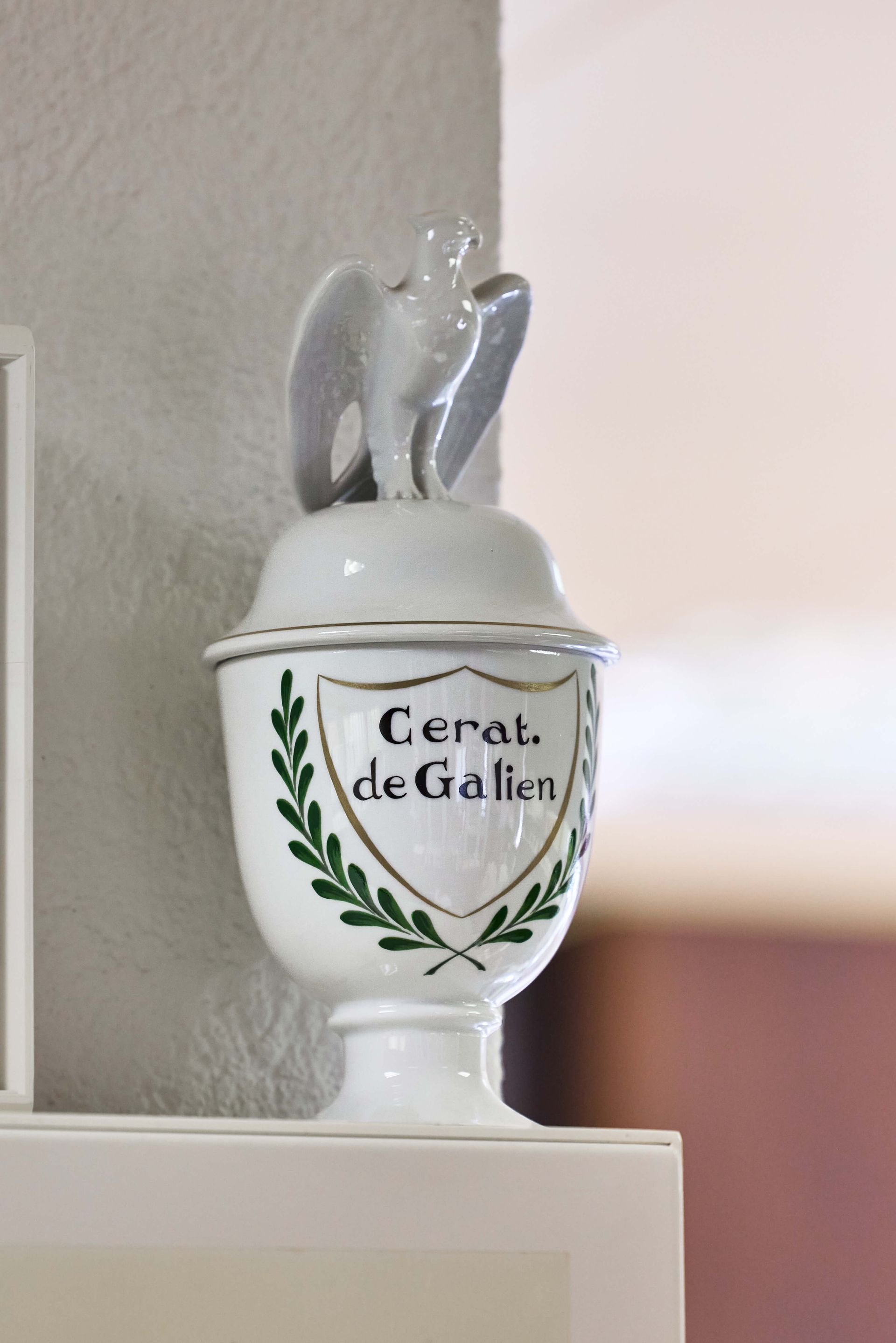 Eine Keramikdose mit einem Vogel oben drauf, auf dem „Cerat de Galien“ steht