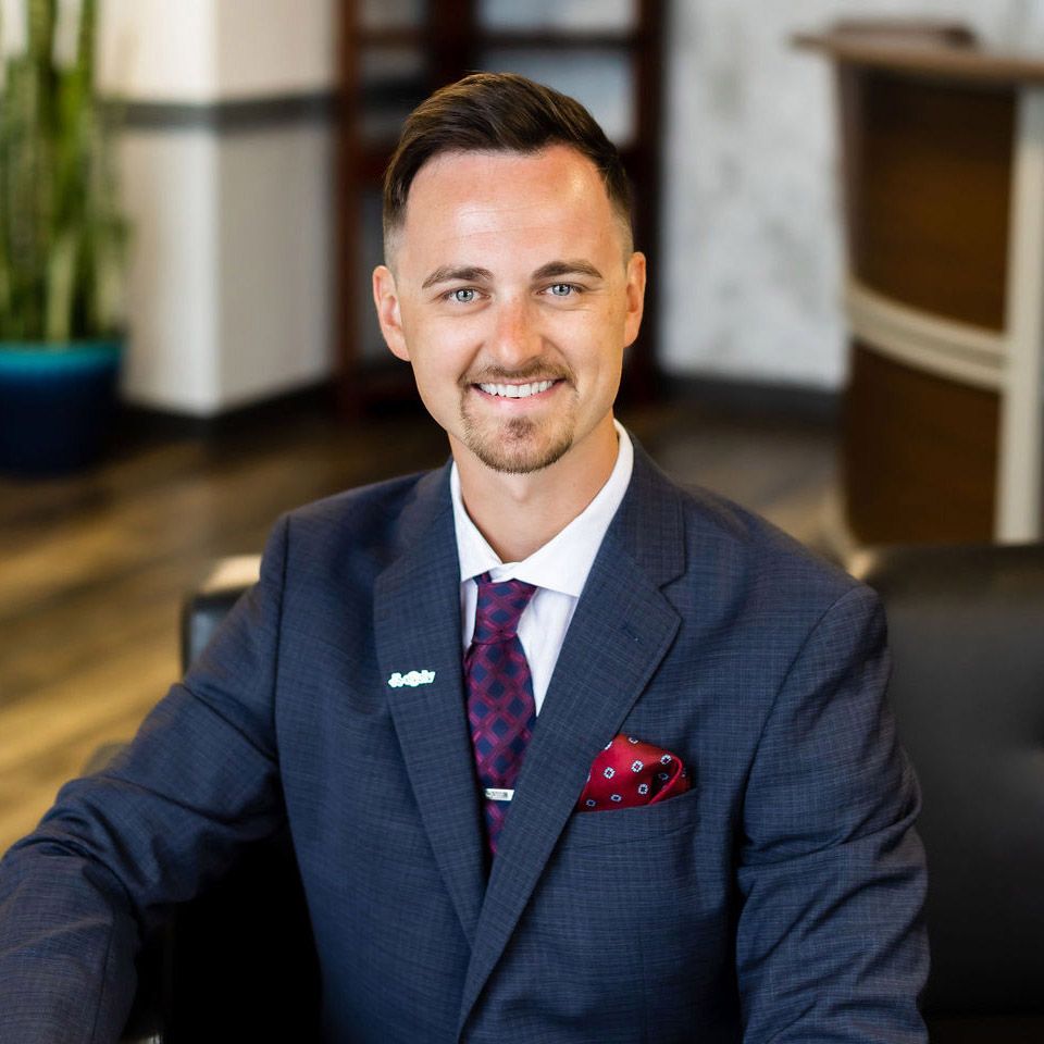 A man in a suit is sitting in a chair and smiling.