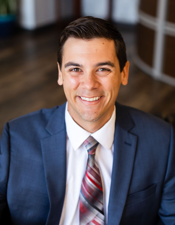 A man in a suit and tie is smiling for the camera.