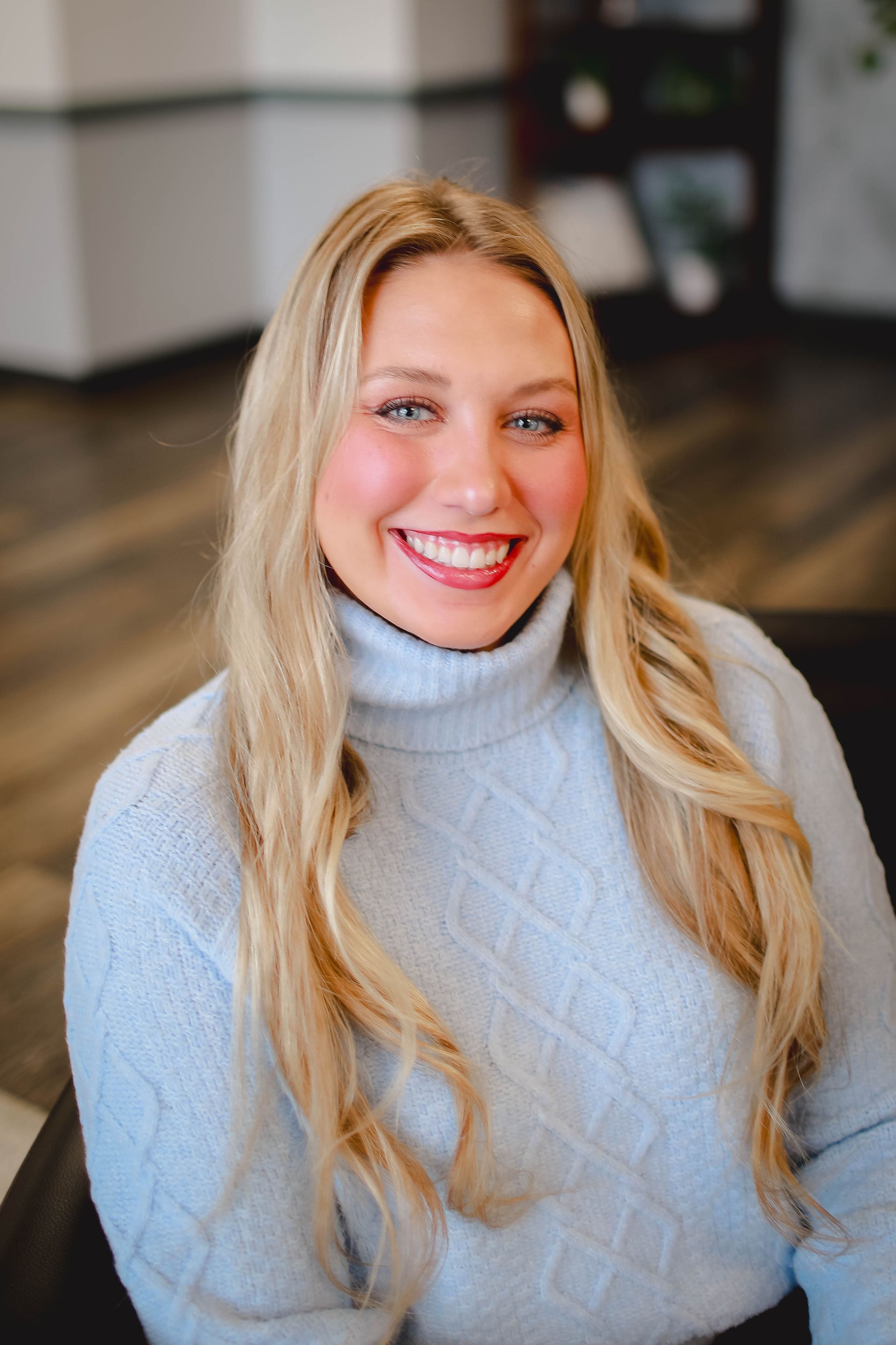 A woman with long blonde hair is wearing a white shirt and a black jacket.