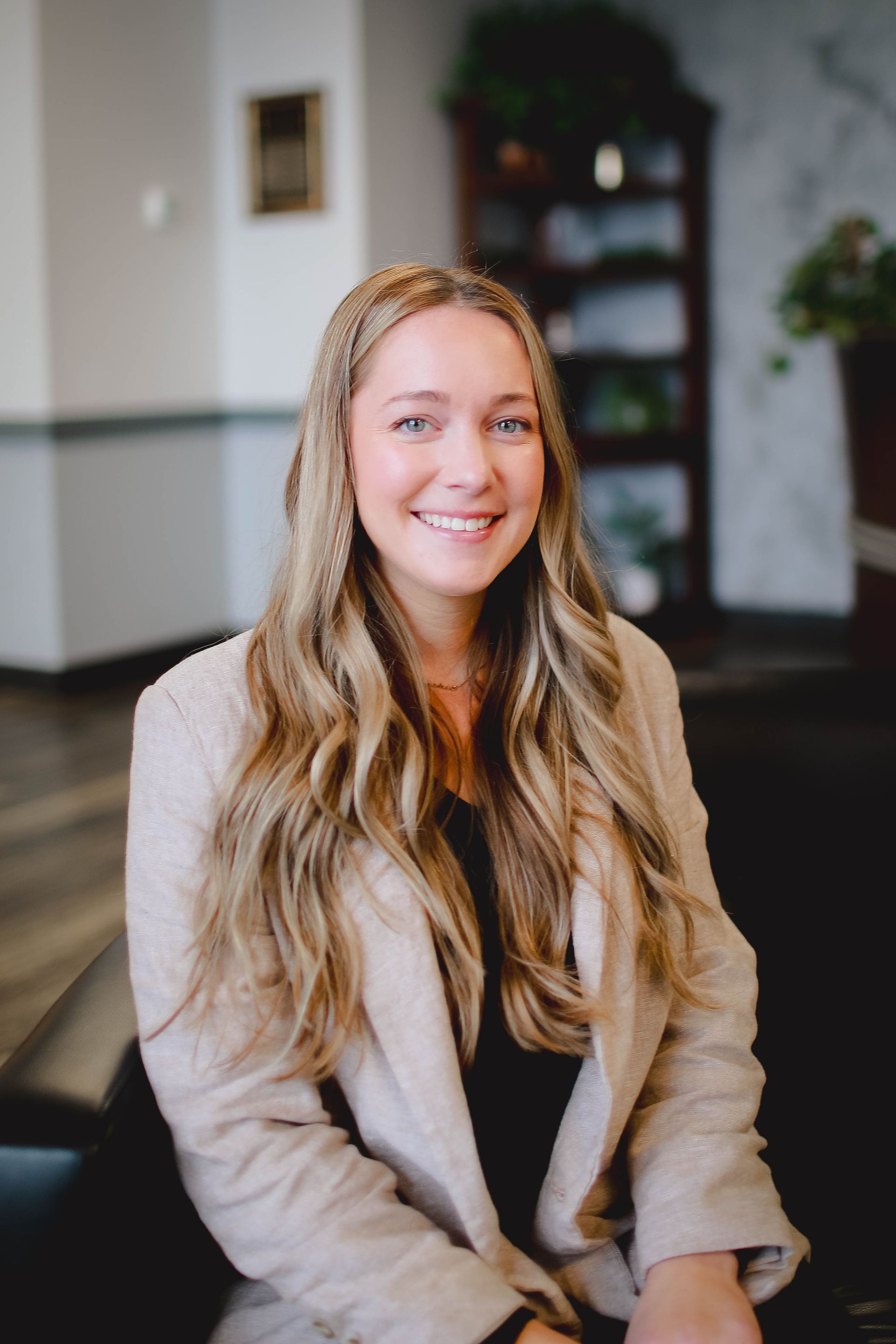 A woman is sitting on a couch and smiling for the camera.