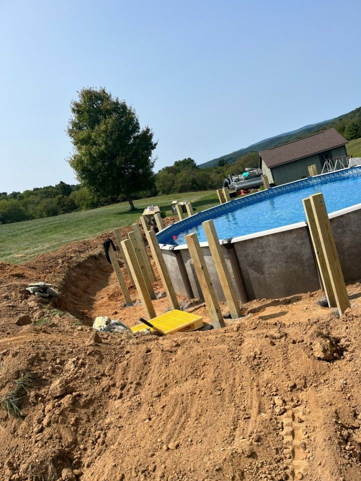 Pool under construction on a hillside, with wooden support beams and an excavated area.