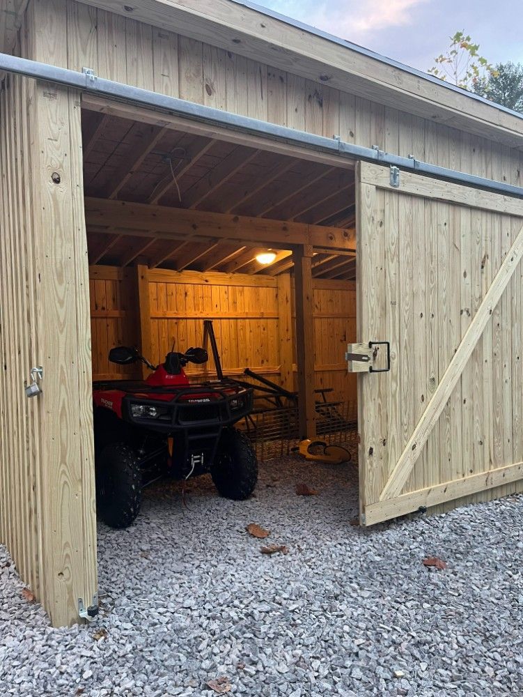 Wooden shed with sliding doors, ATV parked inside.
