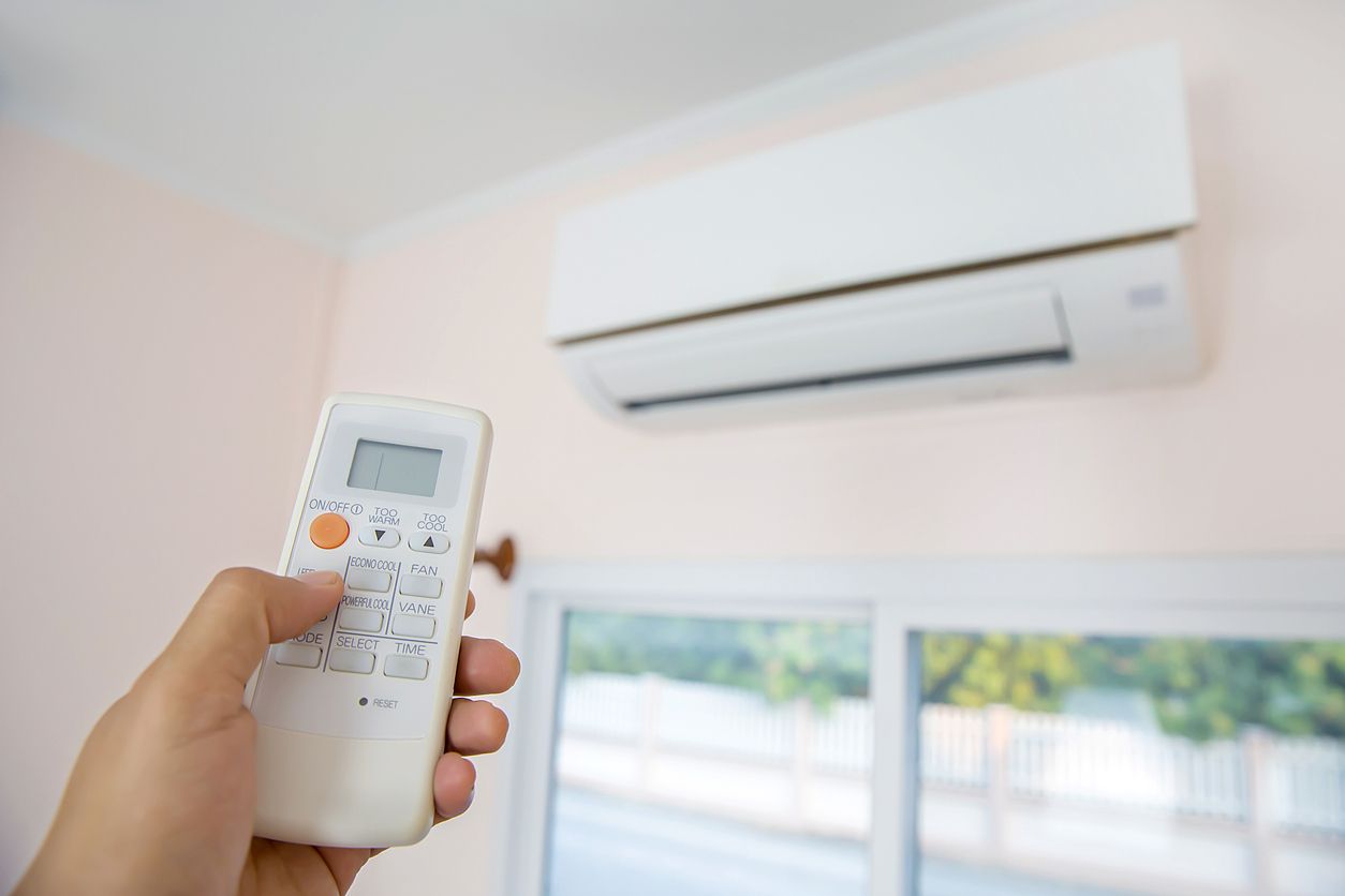 a person is holding a remote control in front of an air conditioner .