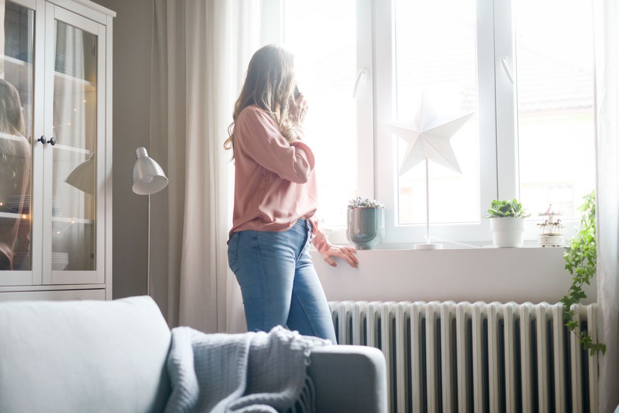 a woman is standing in a living room looking out of a window .