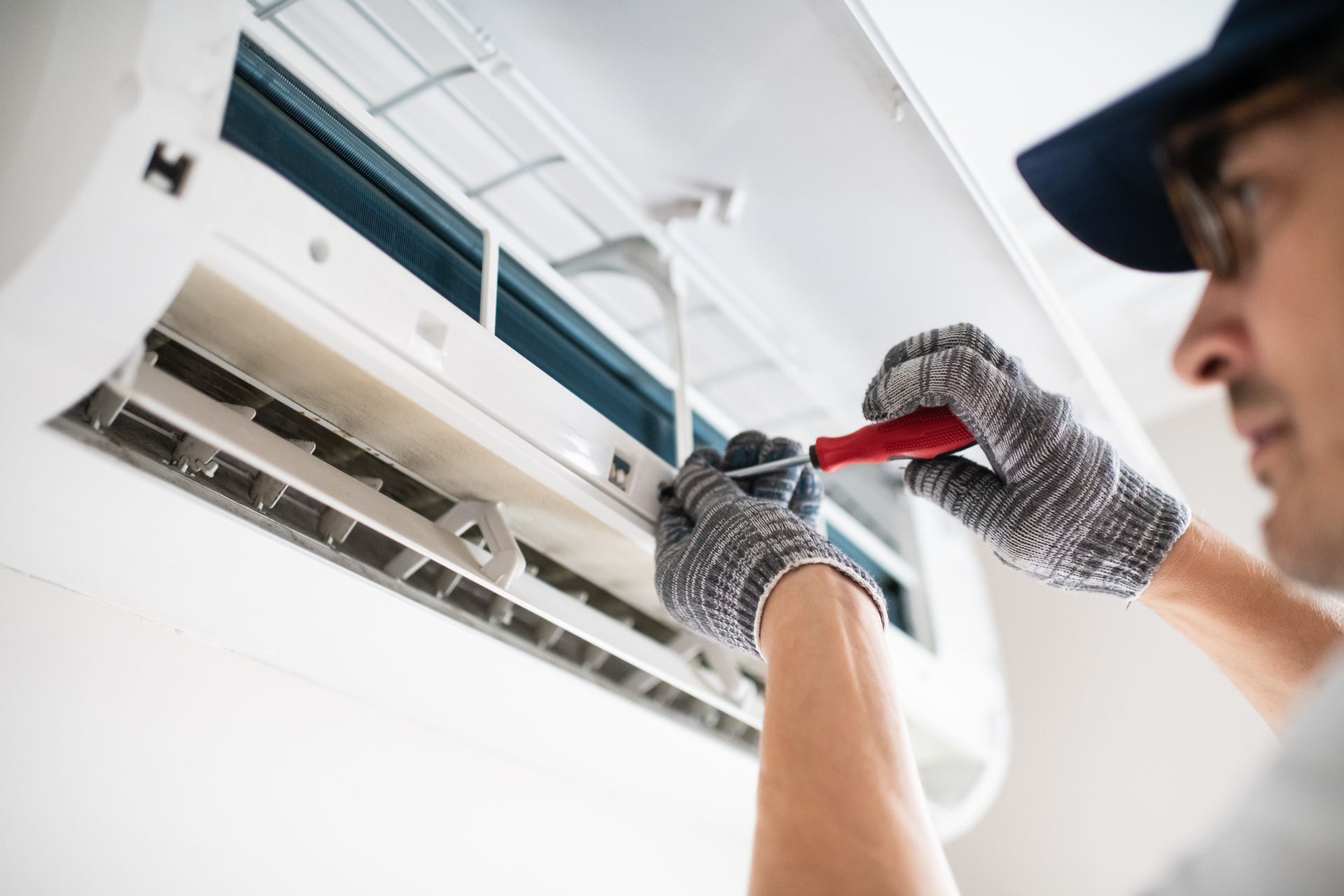 HVAC technician repairing a residential air conditioning system to diagnose uneven cooling issues.