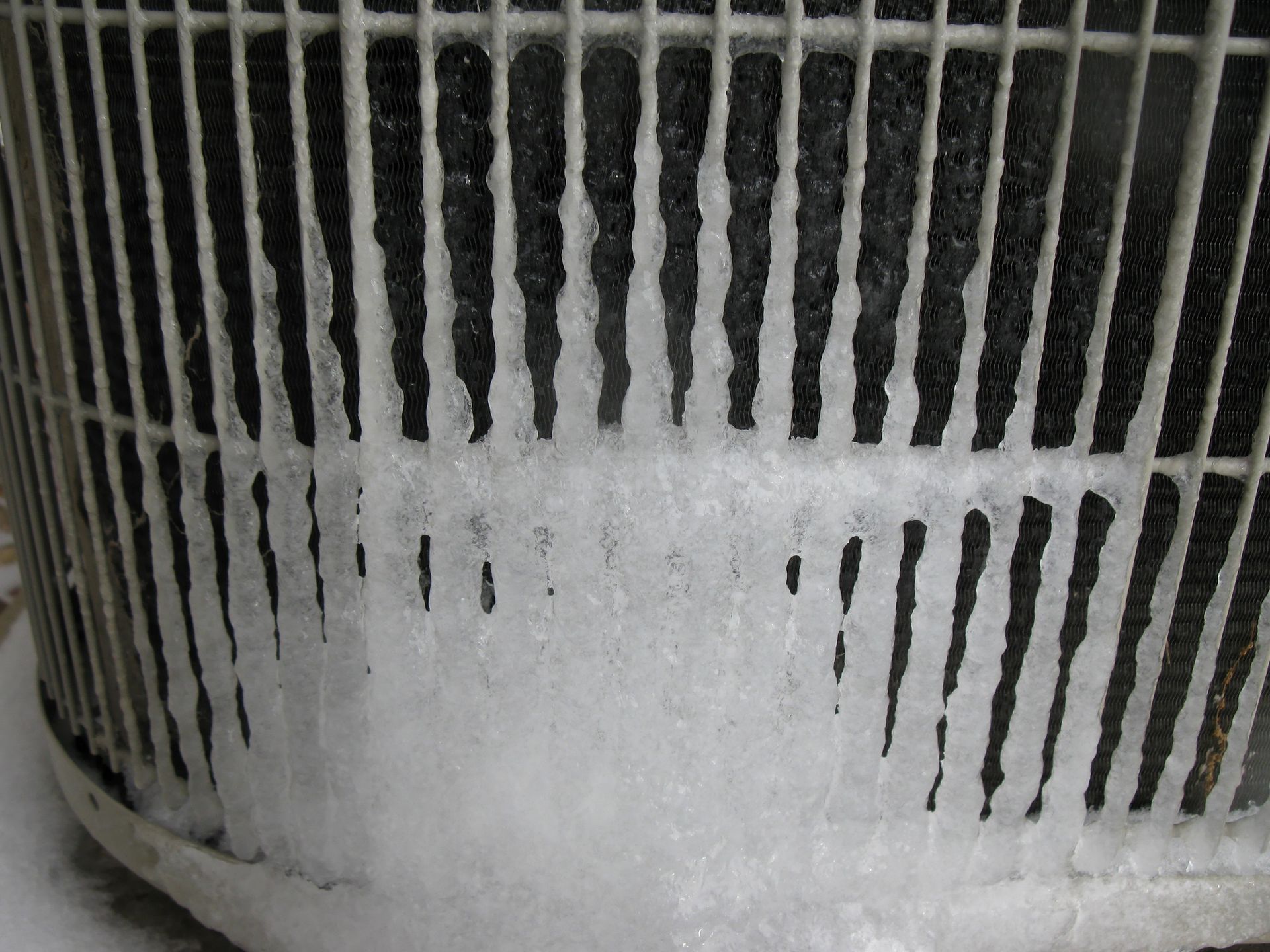 Frost-covered outdoor heat pump unit showing iced coils during winter at a Magnolia, TX home.