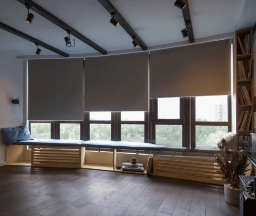 Interior with automated gray shades, wooden floor, and a built-in bench.