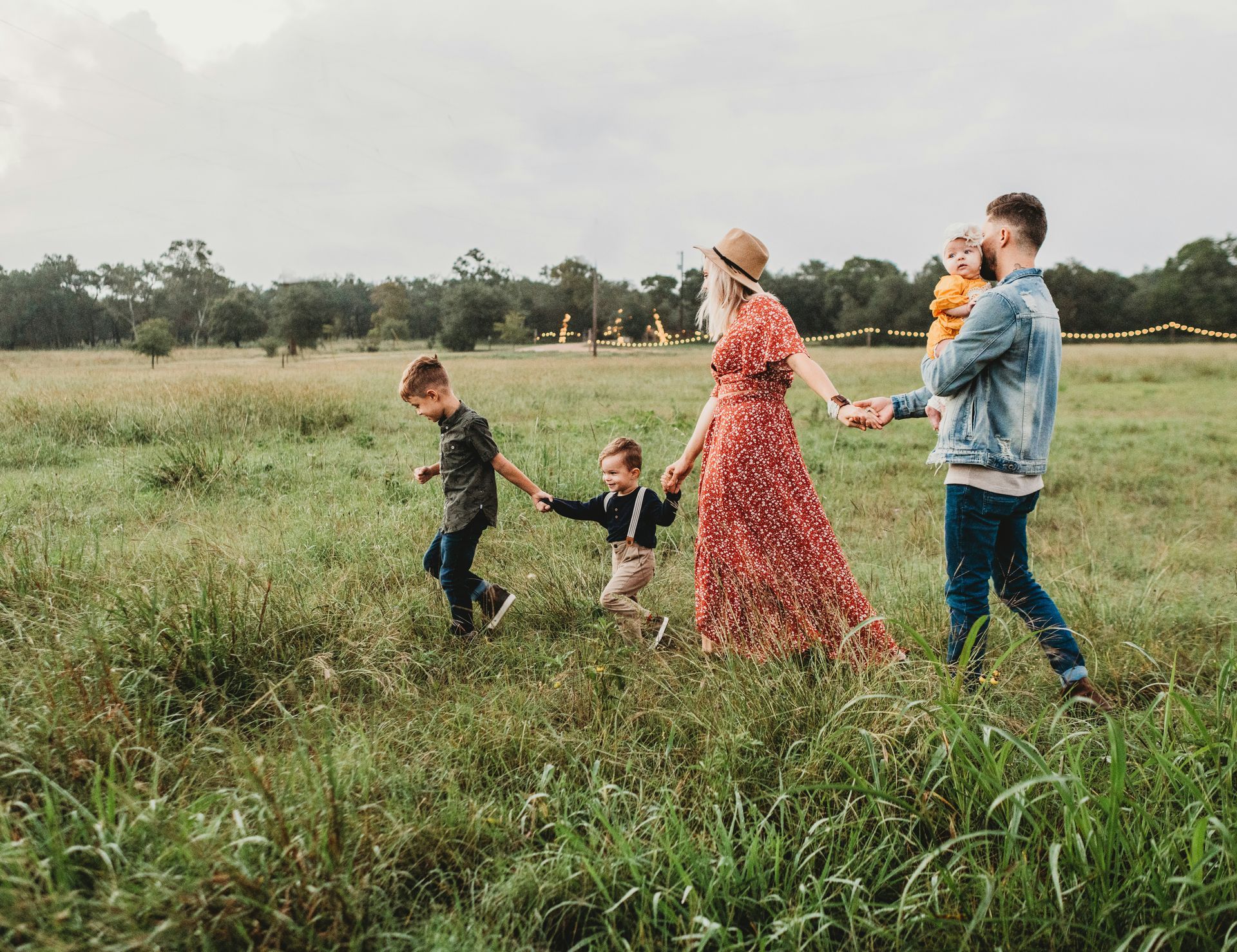 Family walking together through an open grassy field, holding hands and enjoying time outdoors