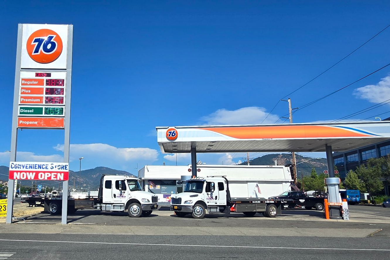Modern roadside gas station services with red canopy and fuel pumps under blue sky. 76 gas station with trucks parked under the canopy on a sunny day
