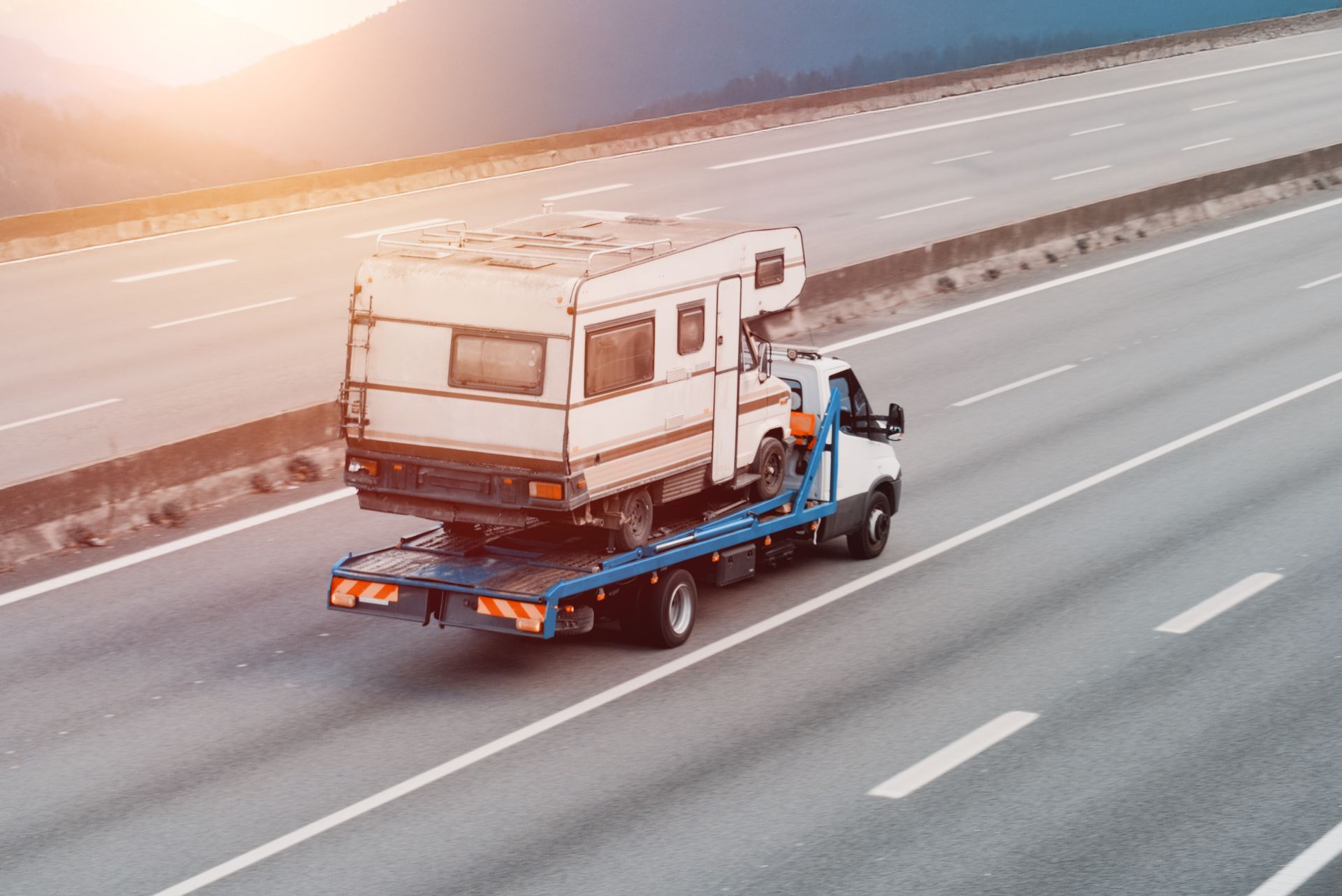 Tow truck in action showcasing recreational vehicle towing for vintage camper roadside assistance.