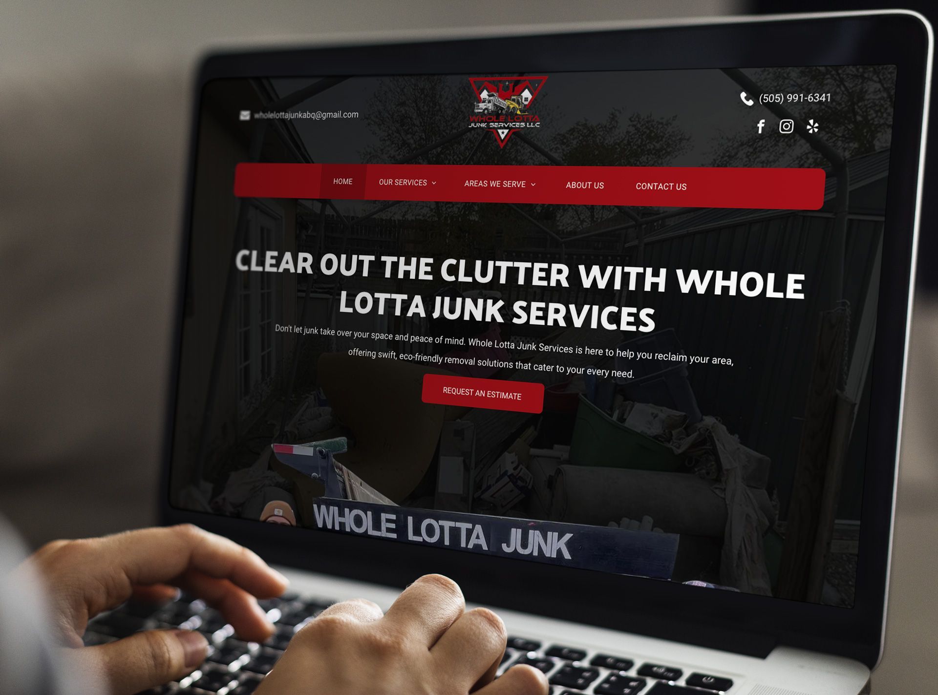Person using a laptop, displaying the Whole Lotta Junk website. Website banner in red and black.