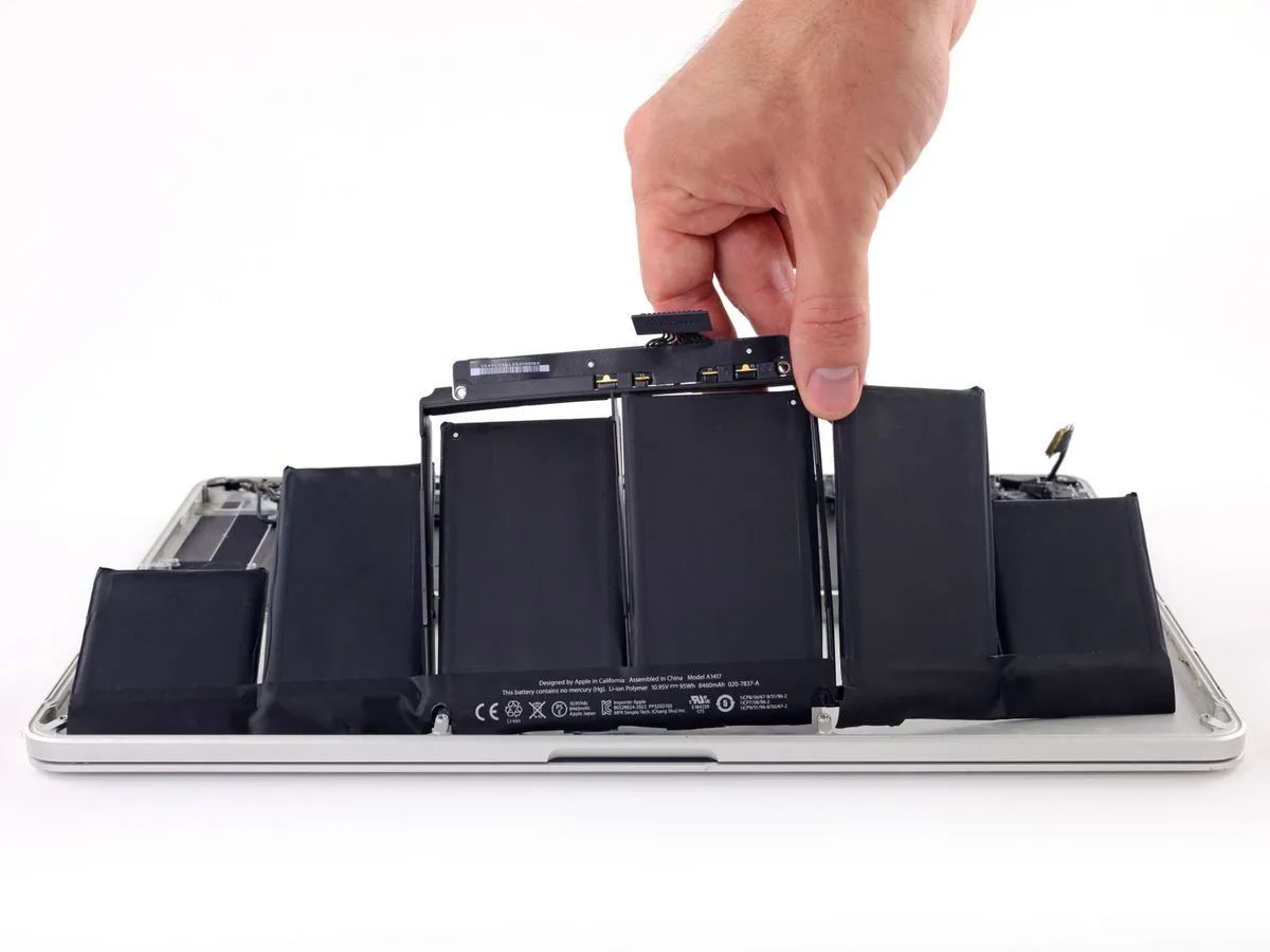 A Person Is Removing A Battery From A Laptop
