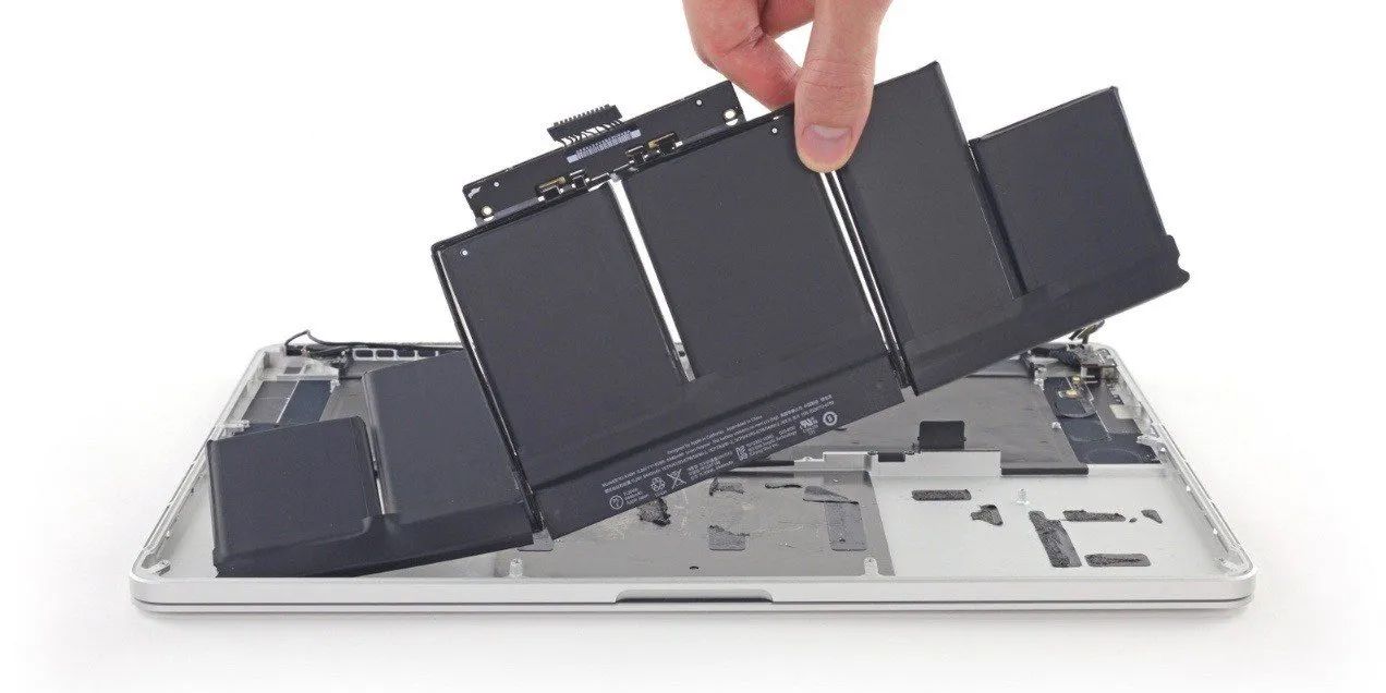 A Person Is Taking A Battery Out Of A Laptop