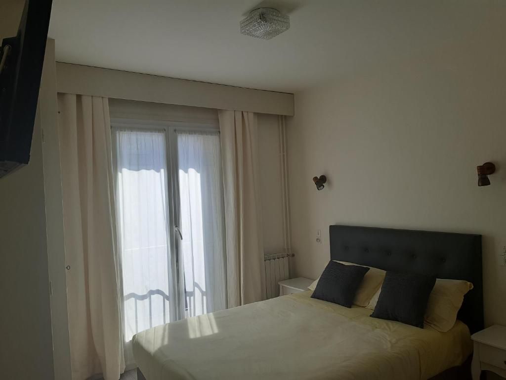 Une chambre avec un lit, une table de chevet, une télévision et des portes coulissantes en verre.