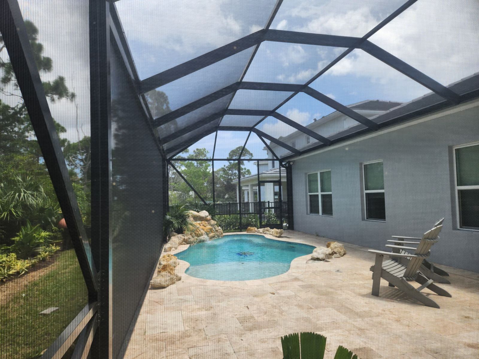 White screened-in pool enclosure with a partially filled pool. Sky and trees are visible in the background.