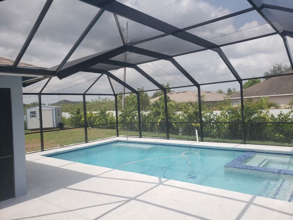 Pool enclosed in black screened structure; blue water, white patio.