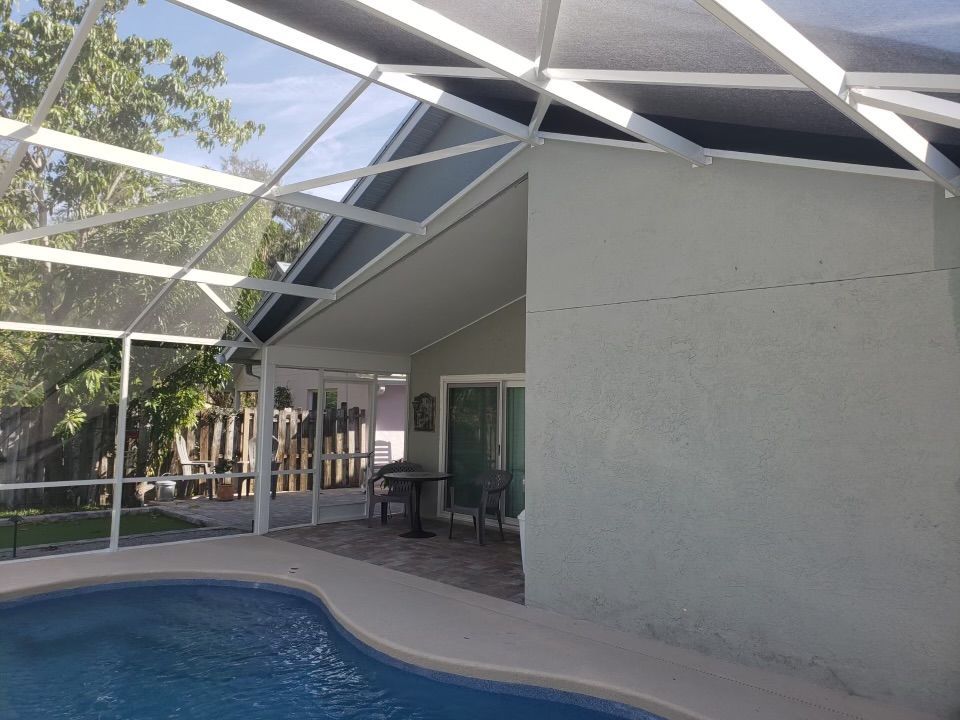 Pool and patio enclosure with a white frame, blue pool, and light green walls.