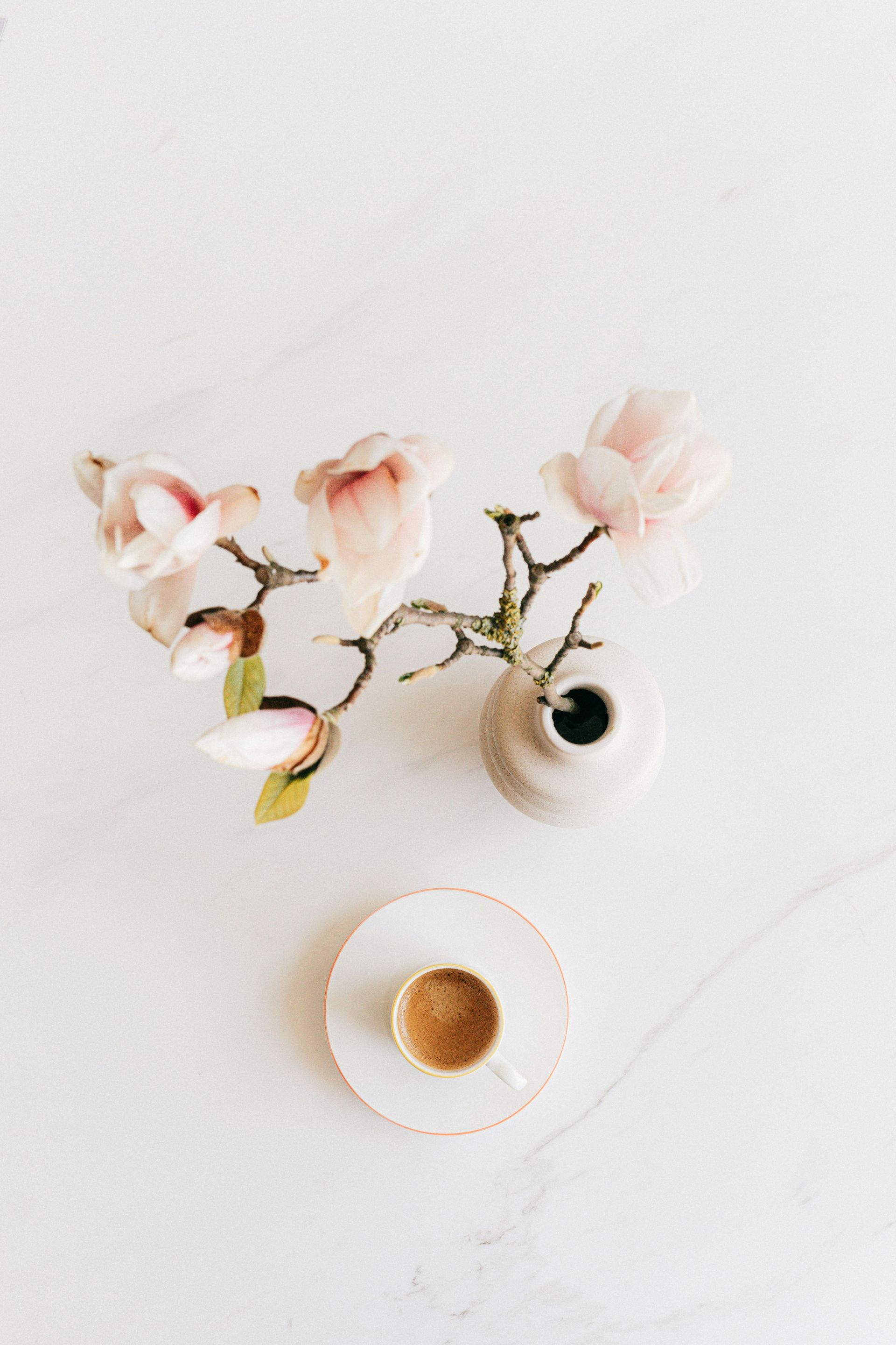 Eine Tasse Kaffee und eine Vase mit Blumen auf einem Tisch.