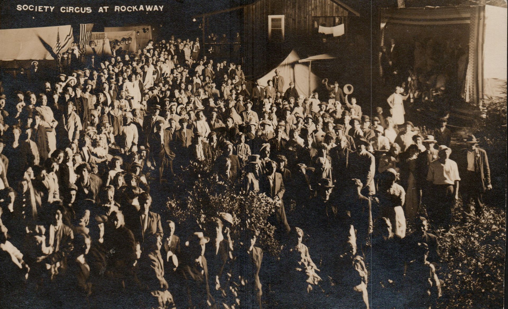 Large crowd gathered at a nighttime outdoor event, illuminated by lights.