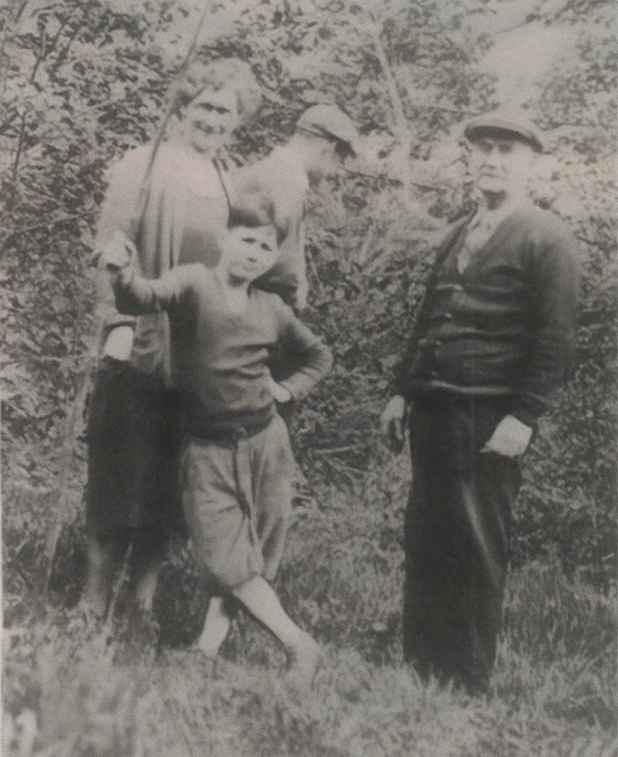 Three people standing outdoors in front of dense bushes