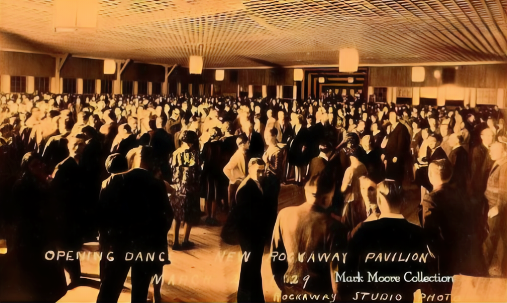 Large crowded indoor event hall with many people seated under warm lighting and a patterned ceiling