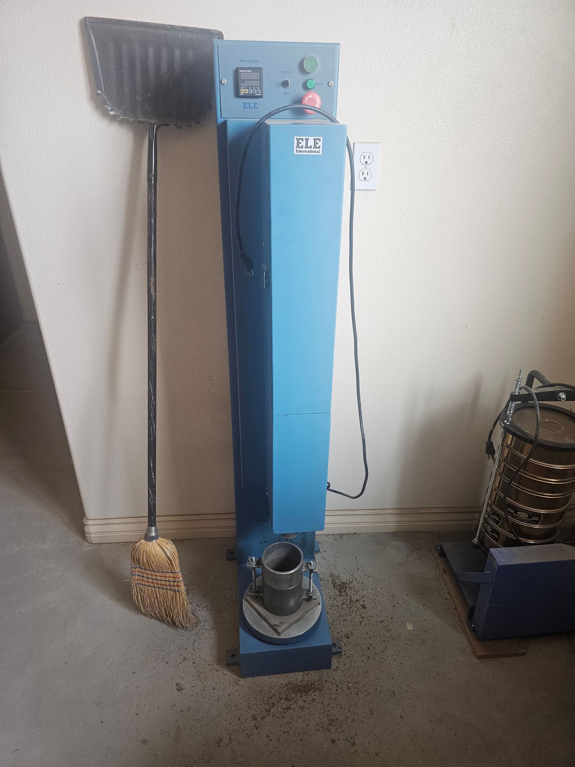 A blue machine with a broom and shovel next to it