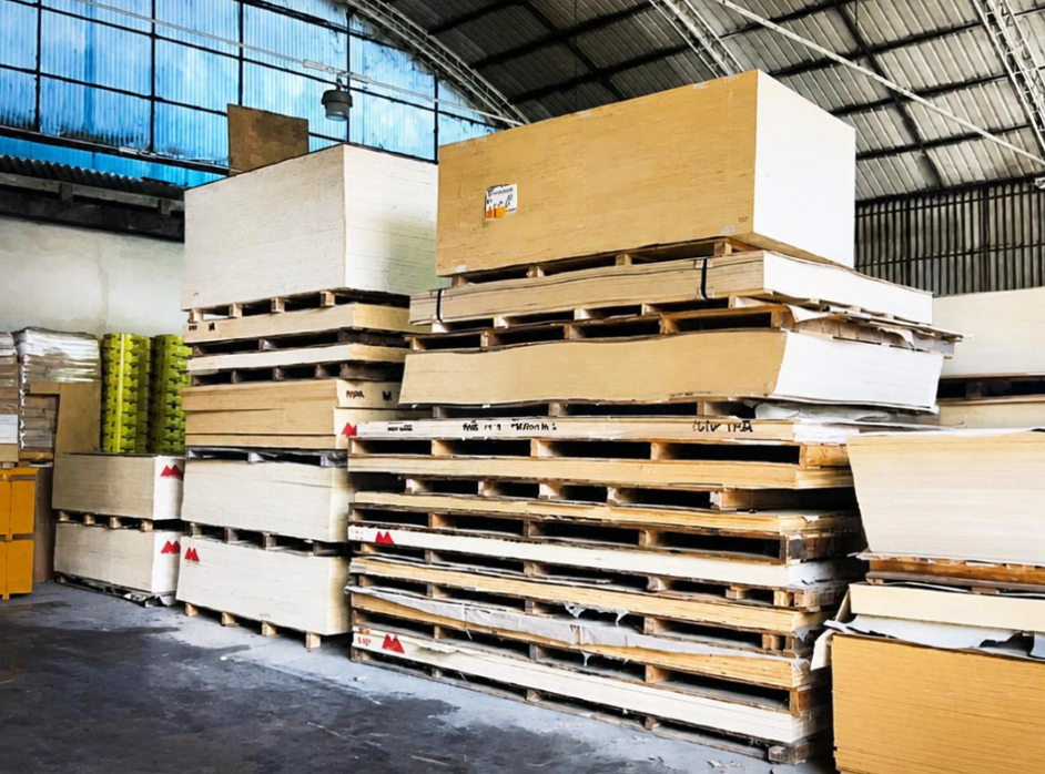 Pile di pallet di legno e grandi scatole riposte in un magazzino con tetto in metallo