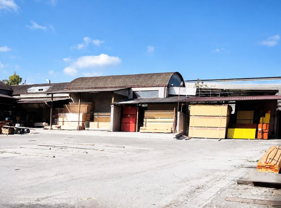 Baia di carico di un magazzino industriale con portoni avvolgibili chiusi e piazzale in cemento vuoto sotto un cielo azzurro
