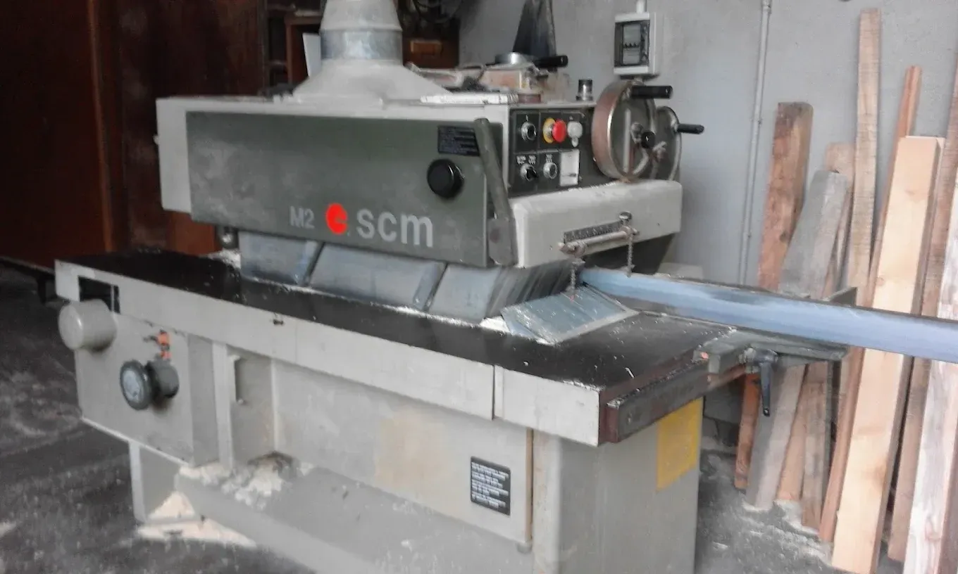 Macchina industriale per la lavorazione del legno, con sistema SCM, in un’officina: grigia, con logo rosso e comandi in metallo.